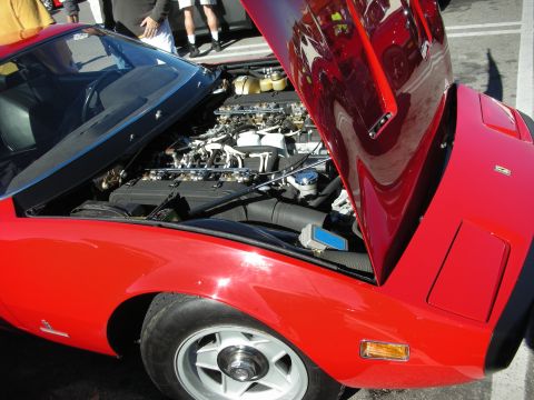 1998 Ford Crown Victoria - red mid-engine sports car with pop-up headlights sits with its rear engine lid raised, exposing the engine at a car show.