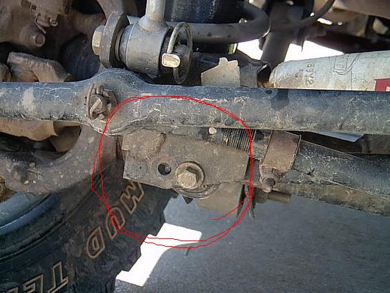 Close-up of a truck front axle steering knuckle with a red circle marking a part