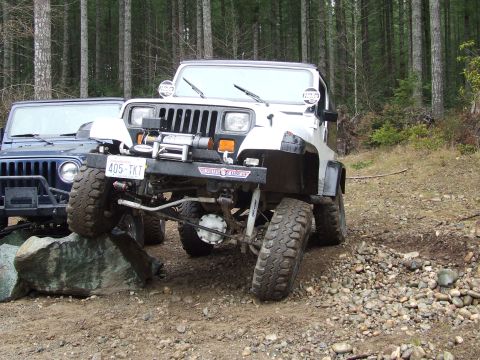 1991 Jeep Wrangler - Two Jeeps navigating a rocky trail in a forest setting.