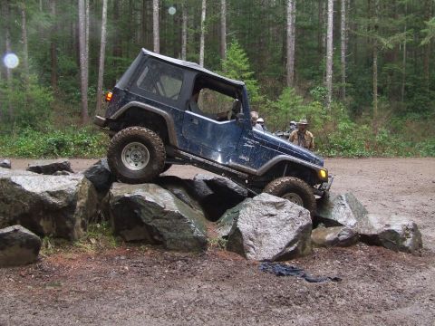 1991 Jeep Wrangler - 1991 Jeep Wrangler navigating a rocky obstacle course in a wooded area.