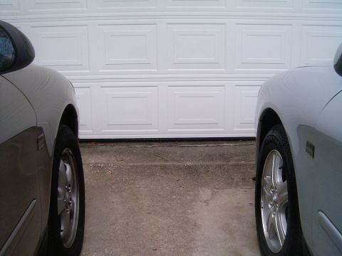 2002 Ford Taurus - Two cars are parked side-by-side in front of a white garage door.