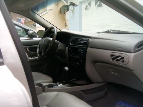 2002 Ford Taurus - The interior of a car is shown, with a view of the dashboard and steering wheel. Another vehicle is visible outside.