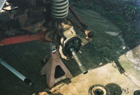 1978 Ford Bronco - Close-up of a vehicle's front axle and suspension components, supported by jack stands.