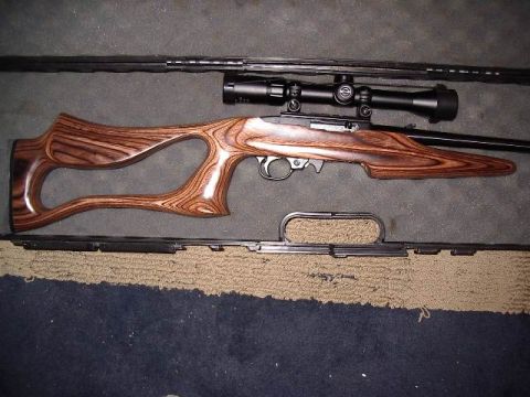 1985 Ford Bronco - A rifle with a distinctive wooden stock and a mounted scope is displayed on a mat.
