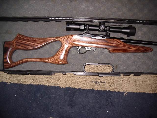 Rifle with wooden stock and scope, lying on a mat