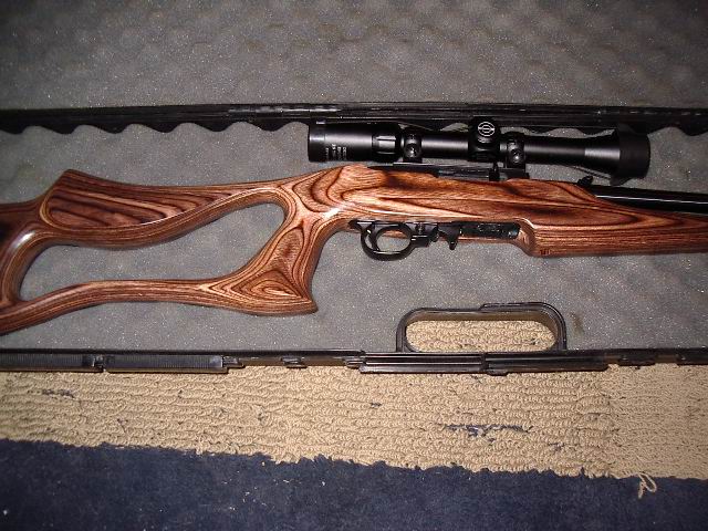 Rifle with a wooden stock and scope in a case