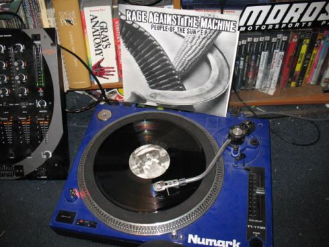 1997 Ford Crown Victoria - A blue Numark turntable is set up with a record playing, surrounded by books and music media.