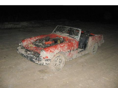 1974 Ford F-100 - A heavily soiled red convertible sits in dirt, its engine exposed and driver's side door absent.