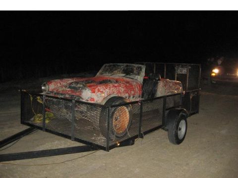 1974 Ford F-100 - A muddy red convertible is transported on a trailer under the cover of darkness.
