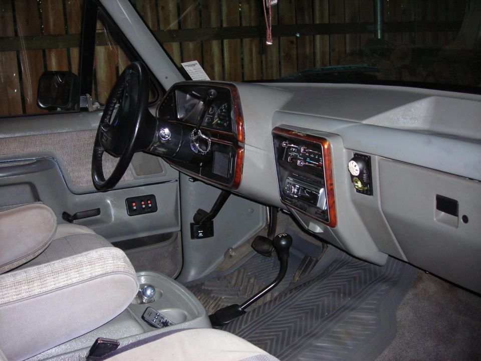 Gray interior of a 1980s truck, showing dashboard, steering wheel, and seats