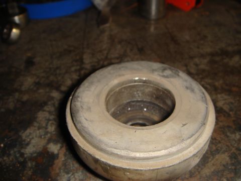 1993 Ford Taurus - A close-up view of a used automotive suspension part resting on a cluttered surface.
