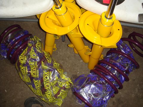 1993 Ford Taurus - Several yellow shock absorbers and purple coil springs are laid out, some still in protective packaging.