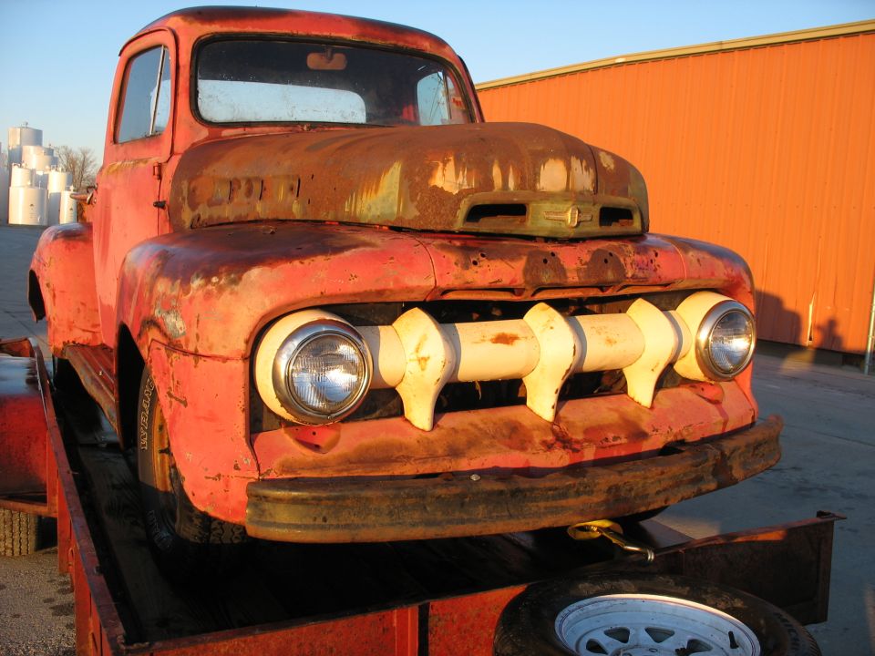 Front view of a rusty red 1952 Ford Pickup truck on a trailer