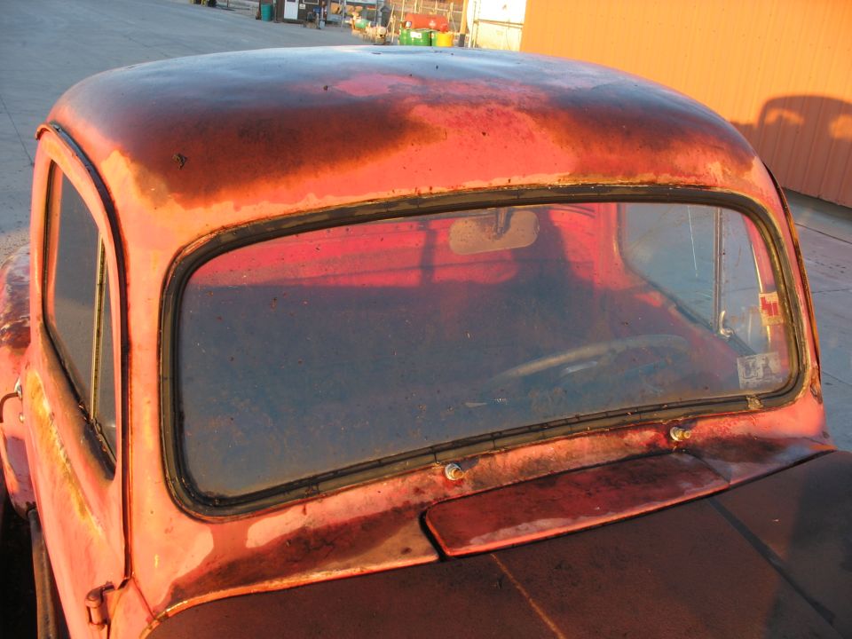 1952 Ford Pickup cab with rusted red paint and cracked windshield