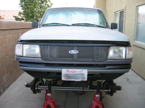 1997 Ford Ranger - A silver 1998 Ford Ranger is elevated on red jack stands with its front wheels removed for maintenance.