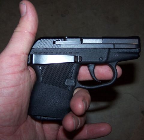 1990 Ford Bronco - A black pistol is held in a hand, with a close-up view of its grip and trigger mechanism.