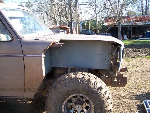 1981 Ford Bronco - Truck with missing front fender and exposed wheel well sits in a rural setting.