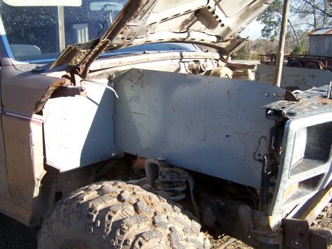 1981 Ford Bronco - Front end of a heavily weathered truck, showing damage and exposed engine components.