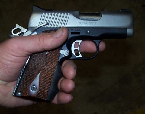 1990 Ford Bronco - A pistol with wood grips and a silver slide is held in a person's hand.