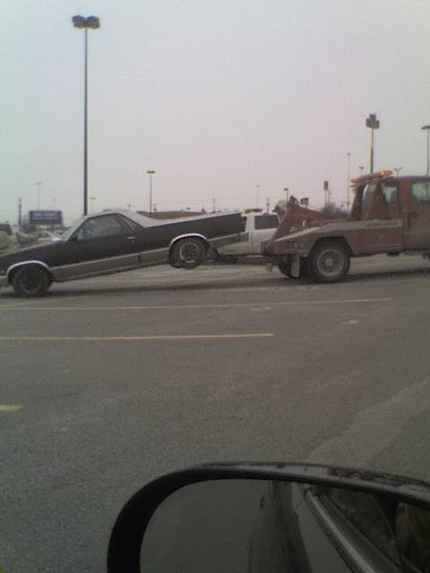 1970 Ford Ranchero - A Ford Ranchero is loaded onto a tow truck in a parking lot.