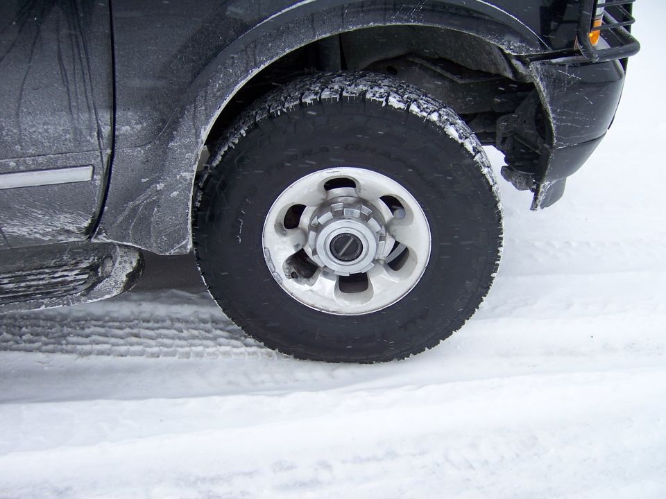 Black SUV tire and fender in snow, close-up side view