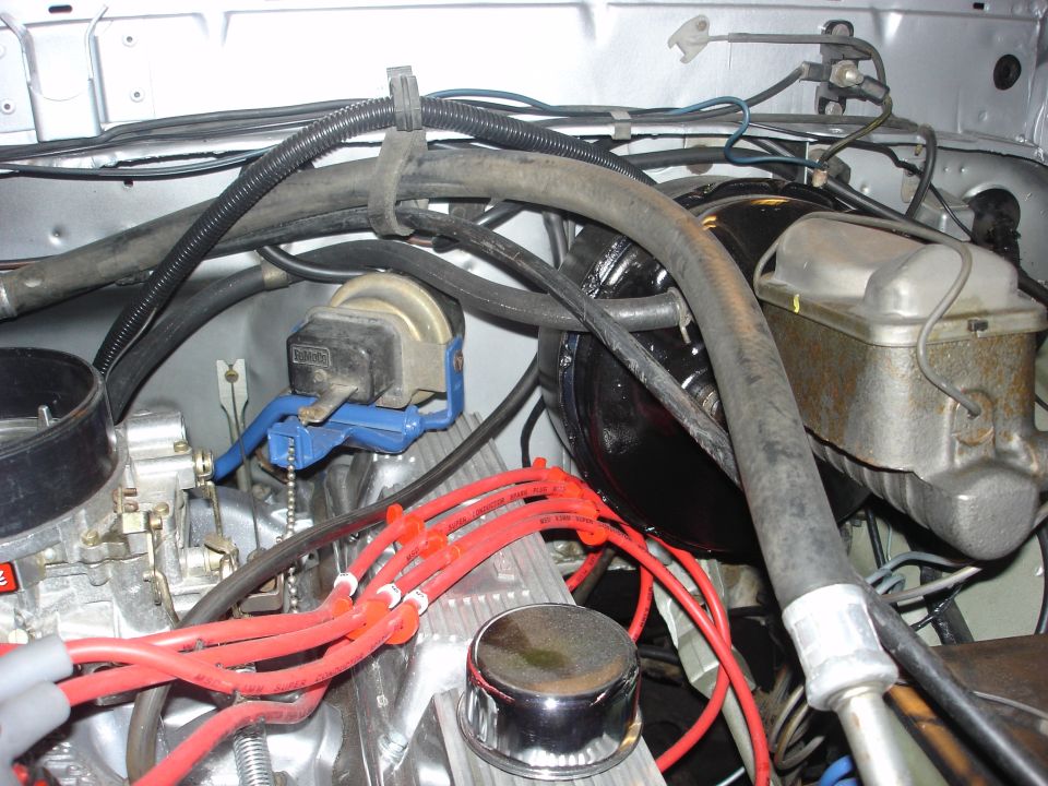 close-up of engine bay with carburetor, spark plug wires, and brake fluid reservoir