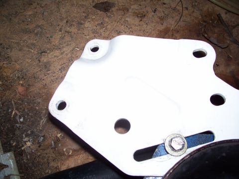 1985 Ford Bronco - A white metal bracket with a bolt and blue washer is shown against a wooden surface.