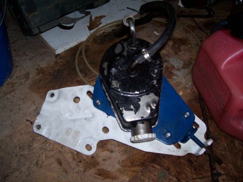 1985 Ford Bronco - A power steering pump assembly is shown on a wooden floor next to a red gas can.