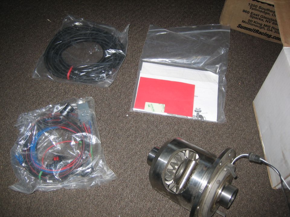 differential and two wiring harnesses laid out on carpet, with a box in background