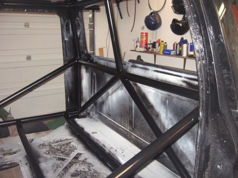 1977 Ford F-150 - The interior of a truck is shown with a custom roll cage installed, obscuring much of the original cabin and bed.
