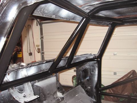 1977 Ford F-150 - A black roll cage is installed inside a vehicle's interior, with a garage door visible in the background.