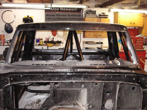 1977 Ford F-150 - The interior of a black truck cab shows a roll cage installed, with tools and equipment visible in the background.