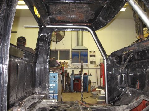 1977 Ford F-150 - Roll cage installation in progress inside a truck, with welding equipment visible in the workshop.
