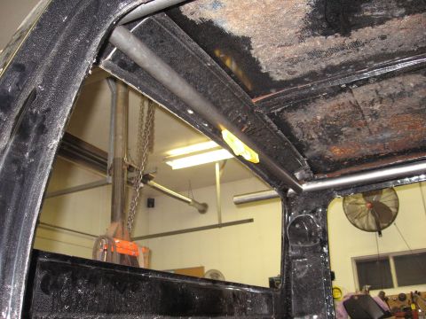 1977 Ford F-150 - The interior of a truck cab shows a custom roll cage installed, with a fan visible in the background.
