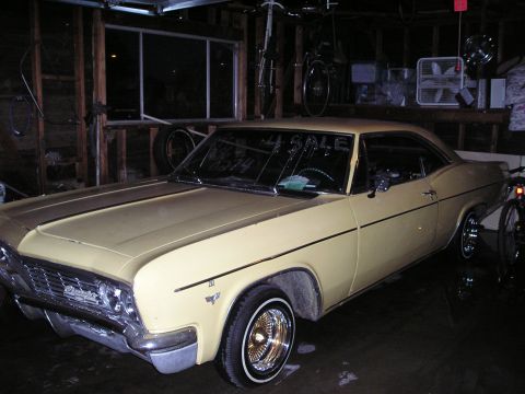1986 Ford Bronco II - A yellow 1965 Chevrolet Impala coupe is parked in a garage with a 'For Sale' sign visible on the windshield.