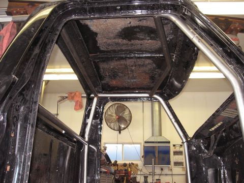 1977 Ford F-150 - The interior of a black truck shows a custom roll cage installed.