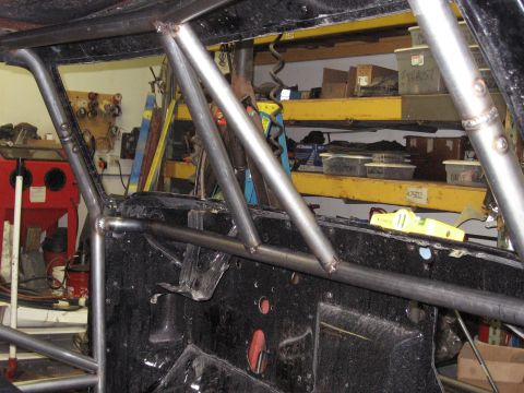 1977 Ford F-150 - Roll cage fabrication in progress inside a vehicle's interior, with workshop shelves visible.