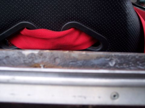 1972 Ford Ranchero - A red seatbelt is visible against a black perforated seat, with metal trim in the foreground.