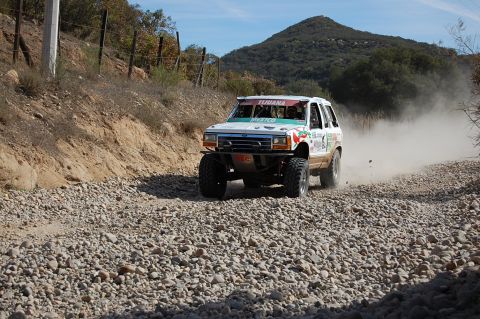 1992 Ford Explorer - This modified 1992 Ford Explorer competes in an off-road race, kicking up a cloud of dust on a gravel road.
