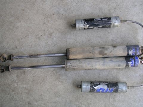 1985 Ford Bronco II - A collection of Fox Racing Shox shock absorbers, including two longer, weathered units and a shorter, black unit with a braided hose.