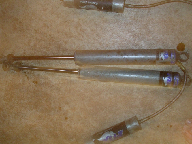 Two Fox shocks and another shock labeled Racing Shox are on a textured surface