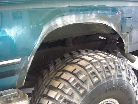 1996 Ford Bronco - Close-up of the rear wheel well and large off-road tire on a teal 1996 Ford Bronco.