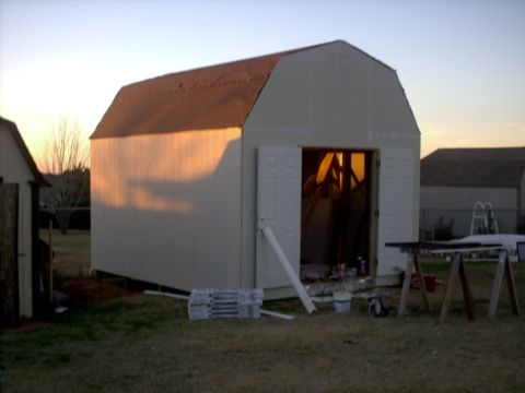 1965 Ford Mustang - A storage shed is shown at sunset with building supplies scattered around the yard.