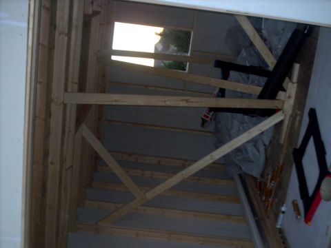 1965 Ford Mustang - Interior view of a garage under construction with wooden framing and a window.