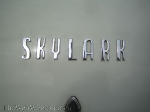 1990 Ford Bronco - Chrome block-letter SKYLARK emblem mounted on a cream-painted automotive body panel.