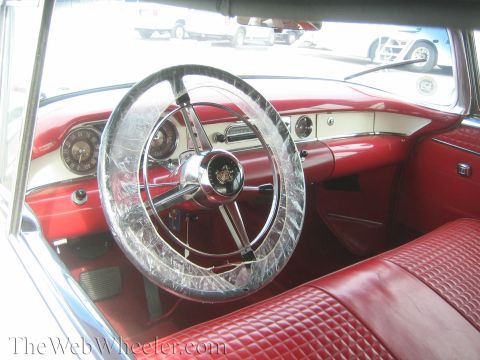 1990 Ford Bronco - Interior of a classic car with red-and-white upholstery and a chrome steering wheel still wrapped in protective plastic.