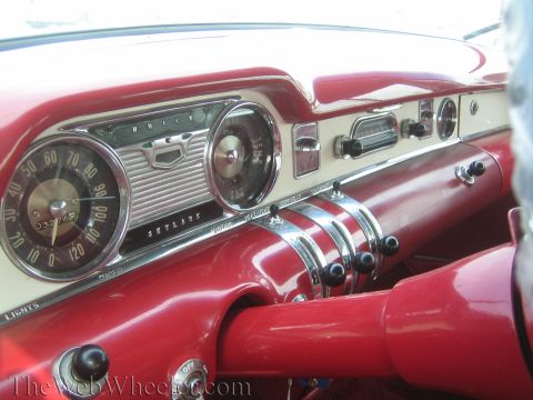 1990 Ford Bronco - Close-up of a Buick Skylark dashboard with chrome bezels, a round speedometer and bright red painted trim.