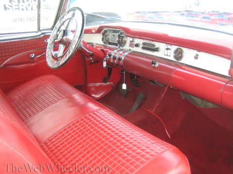 1990 Ford Bronco - Interior of a classic convertible showing bright red tufted upholstery, a chrome steering wheel and chrome dashboard trim.