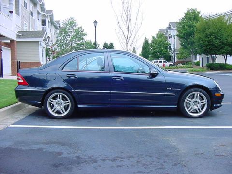 1984 BMW 3 Series - A dark blue sedan is parked in a lot, showing its side profile and V8 badging on the front fender.