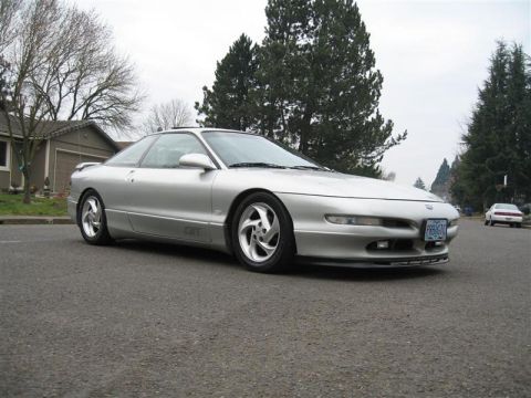 1994 Ford Probe - This silver 1994 Ford Probe GT is parked on a street with trees and houses visible.